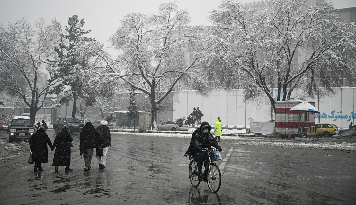Seorang pria mengendarai sepedanya di sepanjang jalan saat hujan salju lebat di Kabul (4/1/2022). Beberapa kecelakaan terjadi pada Senin (3/1) di tengah kondisi lalu lintas yang kacau setelah hujan salju lebat. (AFP/Mohd Rasfan)