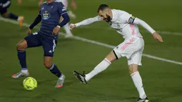 Striker Real Madrid, Karim Benzema menembak bola saat bertanding melawan Celta Vigo pada lanjutan La Liga Spanyol di stadion Alfredo Di Stefano, Minggu (3/1/2021). Real Madrid,  menggeser Atletico Madrid yang punya 35 poin, namun masih menyimpan tabungan tiga laga.(AP Photo/Manu Fernandez)