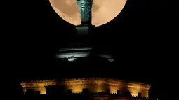 Keindahan fenomena supermoon dari balik replika Patung Liberty di atas Gedung Liberty di pusat kota Buffalo, New York, Minggu (3/12). Selain dinamai Full Cold Supermoon, Supermoon ini juga disebut Big Spirit Moon atau Blue Moon. (AP/Julio Cortez)