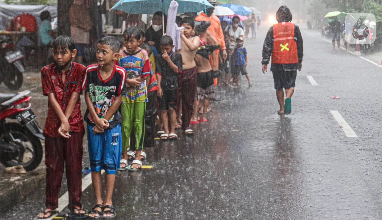 Sejumlah anak-anak antre untuk mendapat takjil gratis di Jalan Cempaka Putih Tengah XXI, Jakarta, Selasa (5/4/2022). Hujan deras yang mengguyur kawasan tersebut tidak menghalangi warga untuk mendapatkan takjil gratis. (Liputan6.com/Herman Zakharia)