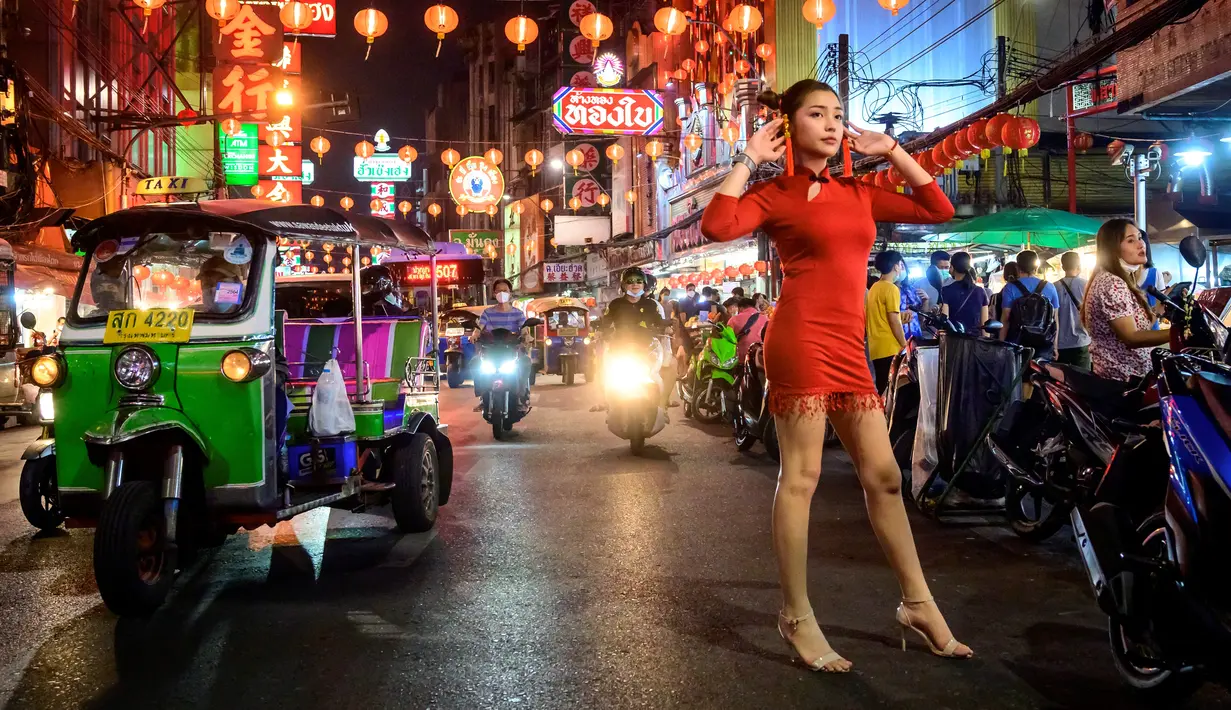 Seorang wanita berpose untuk berfoto di jalan yang didekorasi untuk menyambut Tahun Baru Imlek yang akan datang di Chinatown Bangkok (9/2/2021). Perayaan Tahun Baru Imlek 2021 di Chinatown Yaowarat Bangkok secara resmi dibatalkan menurut Administrator Metropolitan Bangkok. (AFP/ Mladen Antonov)