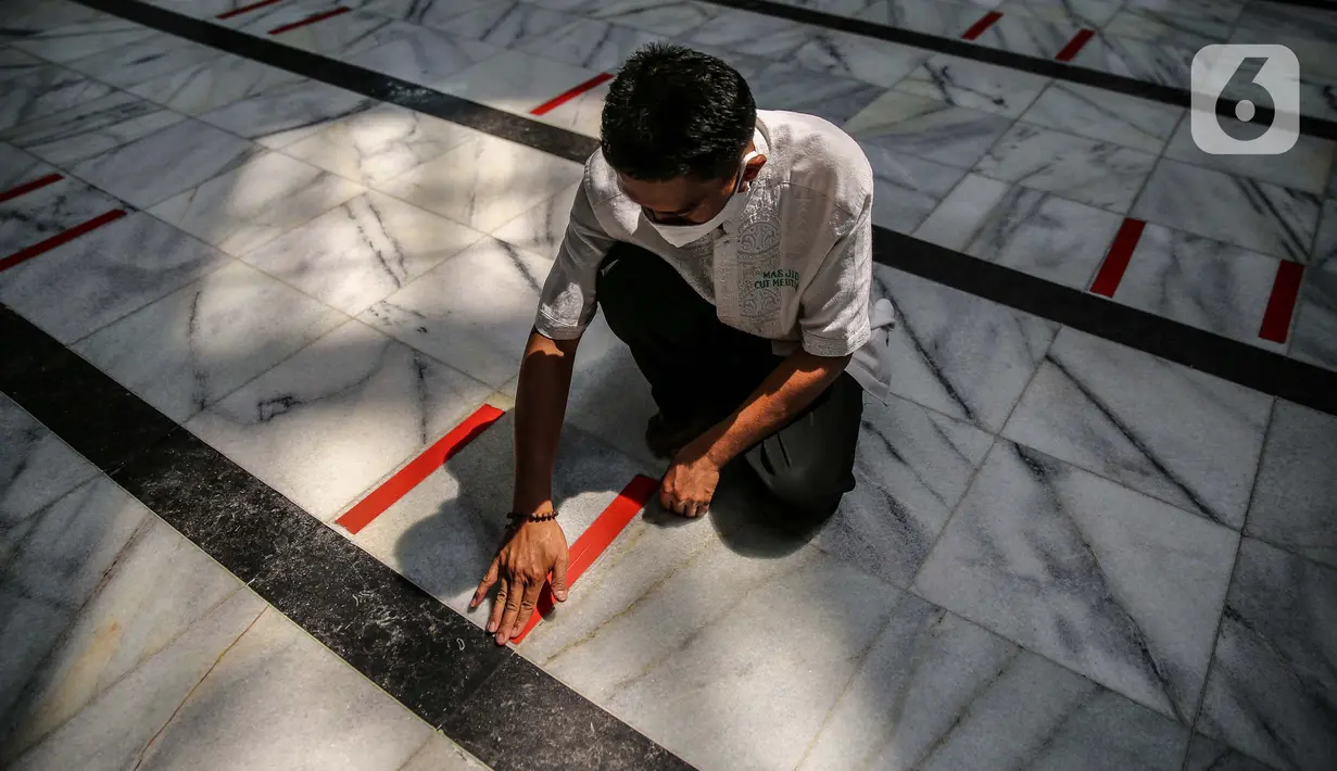 Petugas memasang tanda batas shaf di Masjid Cut Meutia, Jakarta, Kamis (30/7/2020). Masjid Cut Meutia akan menggelar Salat Idul Adha esok hari dengan menerapkan protokol kesehatan pencegahan Covid-19. (Liputan6.com/Faizal Fanani)