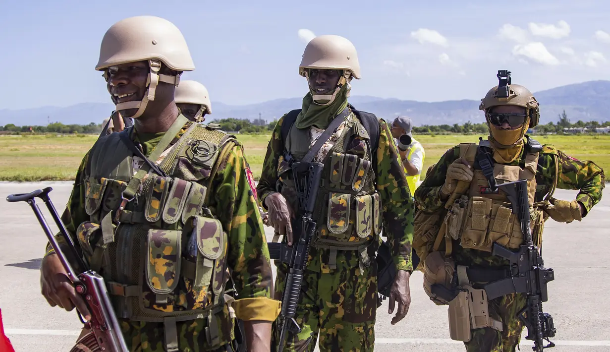 Polisi berseragam Kenya turun dari pesawat Kenya Airways dengan senjata di tangan di Port-au-Prince. (AP Photo/Marckinson Pierre)
