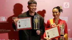 Penyanyi Yura Yunita (kanan) bersama Donne Maulana  berpose memegang piala saat menerima Anugerah Festival Film Indonesia (FFI) 2023 kategori Pencipta Lagu Tema Terbaik di Ciputra Artpreneur, Jakarta, Selasa (14/11/2023). (Liputan6.com/Herman Zakharia)