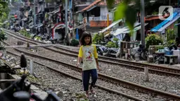 Seorang anak berjalan di bantaran rel kawasan pemukiman padat Pejompongan, Jakarta, Kamis (28/1/2020). Dalam  jangka  waktu  sepuluh  tahun  sejak  tahun  2010,  jumlah  penduduk DKI   meningkat  954  ribu  jiwa,  atau  rata-rata  sebanyak  88  ribu  jiwa  setiap tahun. (Liputan6.com/Johan Tallo)