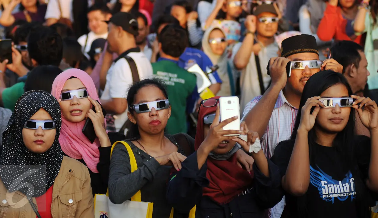 Beberapa warga menggunakan kacamata khusus untuk melihat proses gerhana matahari di sekitar Taman Ismail Marzuki, Jakarta, Rabu (9/3/2016). Di Jakarta, fenomena gerhana matahari 90% bisa diamati selama 2,11 menit. (Liputan6.com/Helmi Fithriansyah)   