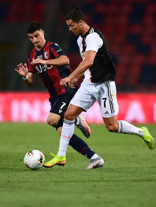 Penyerang Juventus, Cristiano Ronaldo menggiring bola dari kawalan penyerang Bolagna, Riccardo Orsolini pada pertandingan lanjutan liga Serie A Italia di stadion Renato-Dall'Ara di Bologna (22/6/2020). Juventus menang 2-0 atas Bologna. (Miguel MEDINA / AFP)