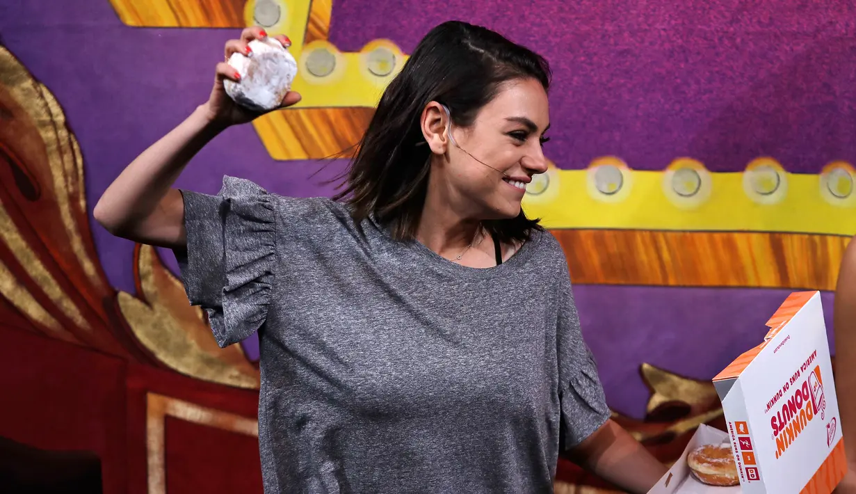 Aktris Mila Kunis melempar donat dalam sebuah presentasi penghargaan di Cambridge (25/1). Mila Kunis dinobatkan sebagai "Woman of the Year" oleh kelompok teater Hasty Pudding. (AP Photo / Charles Krupa)