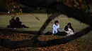 Pasangan berbincang saat menikmati cuaca musim gugur di Gyoen Park di Tokyo (5/12/2019). Taman ini merupakan tempat favorit untuk acara hanami (melihat bunga Sakura). (AFP/Charly Triballeau)