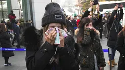 Seorang fans menangis saat mobil yang membawa jenazah Jonghyun SHINee keluar dari rumah persemayaman di Asan Hospital, Seoul menuju tempat pemakaman, Kamis (21/12). Pihak keluarga tidak mempublikasikan lokasi pemakaman Jonghyun SHINee. (JUNG Yeon-Je/AFP)