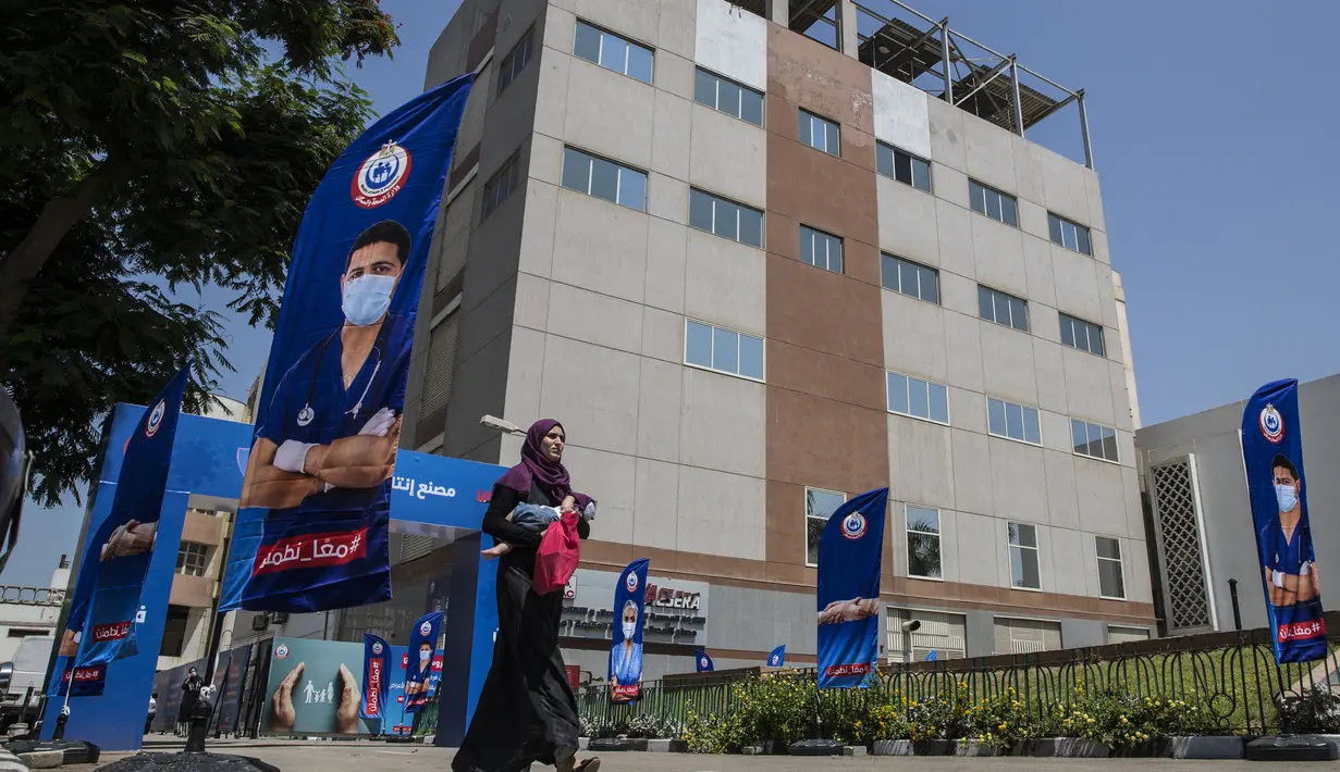 Seorang wanita berjalan di depan pabrik laboratorium pembuatan vaksin Sinovac di laboratorium Vacsera, Kairo, Mesir, Rabu (1/9/2021). Mesir berencana memproduksi satu miliar dosis Sinovac setiap tahun dan menjadikan produsen vaksin terbesar di Timur Tengah dan Afrika. (AFP/Khaled Desouki)