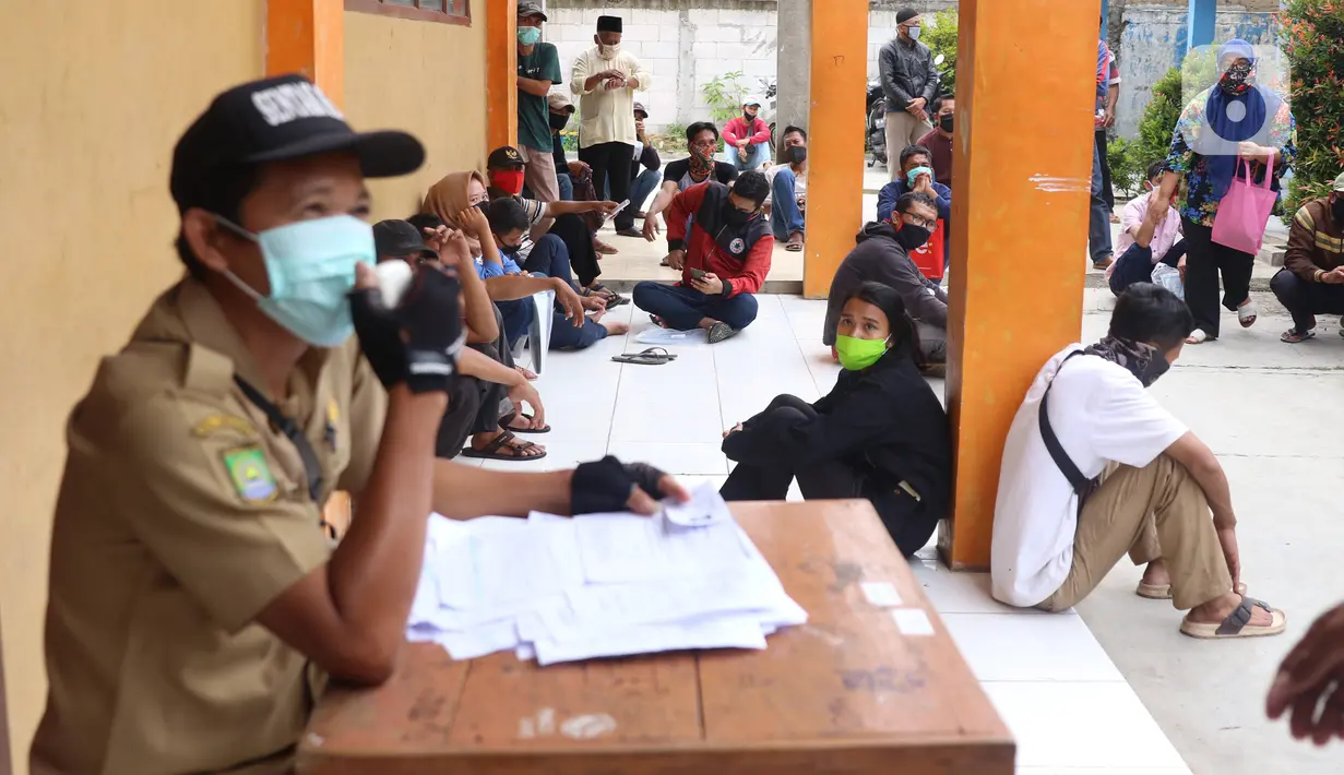Warga mengantre untuk mendapatkan bantuan sosial (bansos) yang diberikan Pemerintah Provinsi Banten di Pinang, Tangerang, Jumat (1/5/2020). Bansos berupa uang tunai sebesar Rp 600 ribu tersebut diberikan kepada warga yang terdampak virus corona COVID-19. (Liputan6.com/Angga Yuniar)