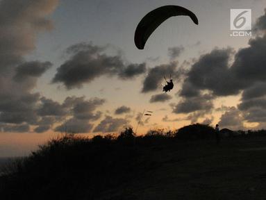 Wisatawan melakukan tandem paralayang di Bukit Riug, Nusa Dua, Bali (30/6). Kegiatan paralayang tandem dengan mengandalkan angin pantai sudah lebih dari satu tahun digemari para wisatawan mancanegara dan lokal. (Merdeka.com/Arie Basuki)
