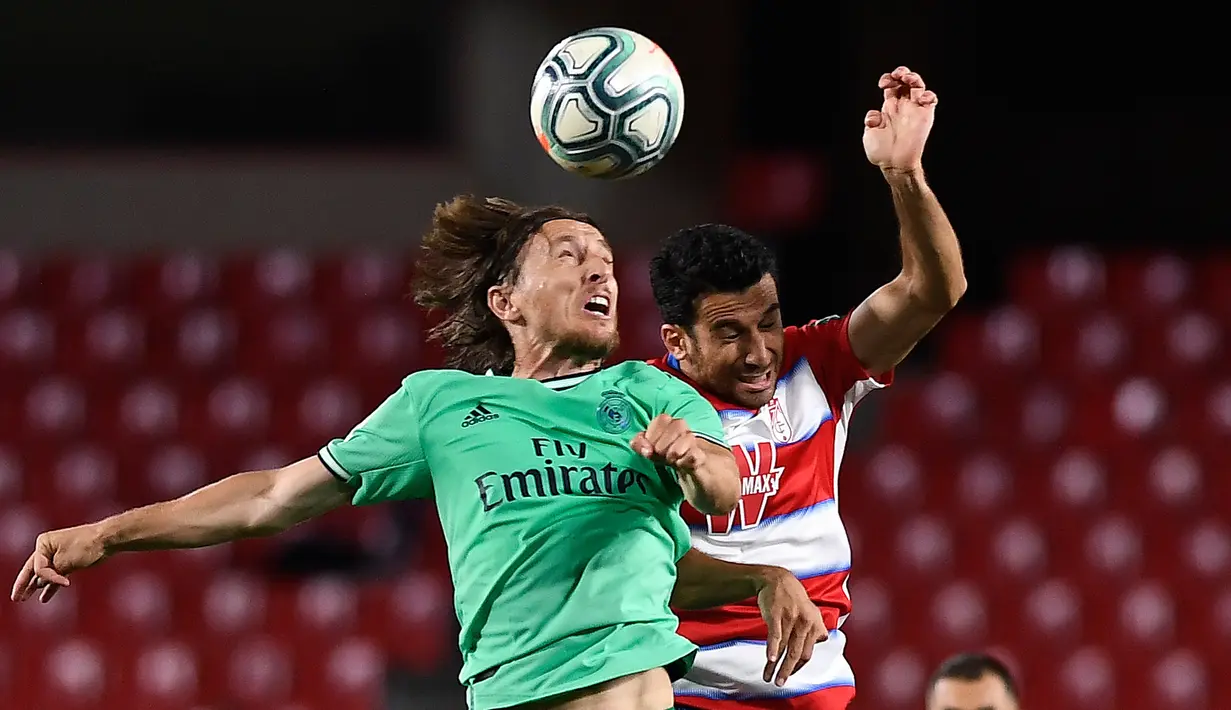 Gelandang Real Madrid, Luka Modric berebut bola udara dengan bek Granada, Ismail Koybasi pada pertandingan lanjutan La Liga Spanyol di stadion Nuevo Los Carmenes di Granada (13/7/2020). Madrid menang tipis 2-1 atas Granada. (AFP/Jorge Guerrero)