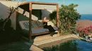 Enzy Storia duduk sambil berpose di pinggir kolam renang sambil menikmati sinar matahari yang menyinari tubuhnya. (Instagram/enzystoria)