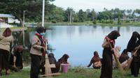Sejumlah siswa Sekolah Dasar Negeri 7 Tilongkabila saat membersihakan bantaran danau perintis (Arfandi Ibrahim/Liputan6.com)