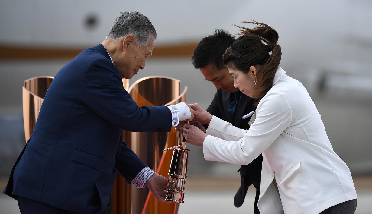 Presiden Olimpiade Tokyo 2020, Yoshiro Mori, menerima api Olimpiade saat tiba dari Yunani di Pangkalan Udara Matsushima, Jepang, Jumat (20/3). Di tengah pandemi virus corona Covid-19, prosesi menuju Olimpiade Tokyo 2020. (AFP/Philip Fong)