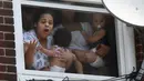 Wanita menggendong bayi menunggu bantuan setelah kebakaran terjadi di dalam gedung apartemen di Hazleton, Pennsylvania (26/7/2019). Pemadam kebakaran kota menggunakan truk menyelamatkan penghuni dari lantai tiga gedung. (Warren Ruda/Hazleton Standard-Speaker via AP)