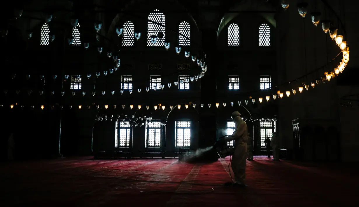 Pekerja mengenakan pakaian pelindung menyemprotkan disinfektan bagian dalam Masjid Suleymaniye yang bersejarah pada hari ketiga Idul Fitri di Istanbul, Selasa (26/5/2020). Beberapa masjid didisinfektan sebelum dibuka kembali pada 29 Mei usai ditutup selama lebih dari enam minggu. (AP/Emrah Gurel)