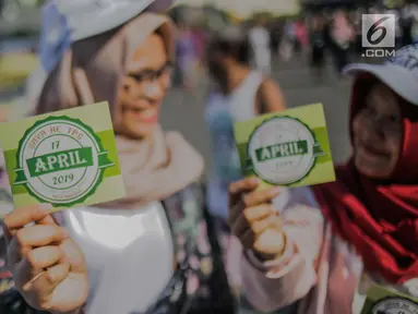 Warga menunjukkan stiker ajakan menggunakan hak pilih pada kegiatan sosialisasi pemilu di kawasan Bundaran HI, Jakarta, Minggu (14/4). Sejumlah Komunitas mensosialisasikan kegiatan pemilu damai tanpa hoaks dan golput menjelang pelaksanaan pemilu 17 April 2019 mendatang. (Liputan6.com/Faizal Fanani)