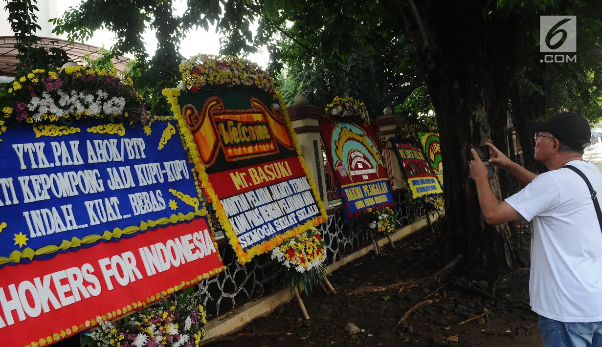 Warga mengambil gambar karangan bunga jelang Basuki Tjahaja Purnama atau Ahok bebas di Mako Brimob, Kelapa Dua Depok, Kamis (24/1). Dalam hitungan jam, Basuki Tjahaja Purnama atau Ahok akan segera menghirup udara bebas. (Liputan6.com/Herman Zakharia)