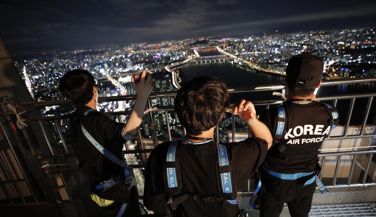 Orang-orang melihat pemandangan malam Seoul saat mereka menginap di tempat berkemah semalam di atap gedung pencakar langit di Seoul, Korea Selatan (7/8/2020).  (AP Photo/Lee Jin-man)