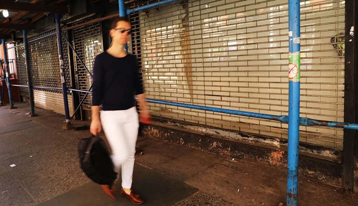 Seorang wanita berjalan di depan sebuah toko yang tutup di West Village, New York (11/4). Bisnis online shop yang terus berkembang membuat sejumlah toko gulung tikar karena sewa yang naik. (Spencer Platt / Getty Images / AFP)