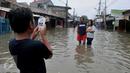 Warga berselfie saat banjir melanda pemukiman warga di Jalan Raya Rawa Buaya, Jakarta, Minggu (28/2/2016). Banjir akibat luapan Kali Mookervart ini menyebabkan ratusan rumah warga tergenang air rata-rata satu meter. (Liputan6.com/Gempur M Surya)
