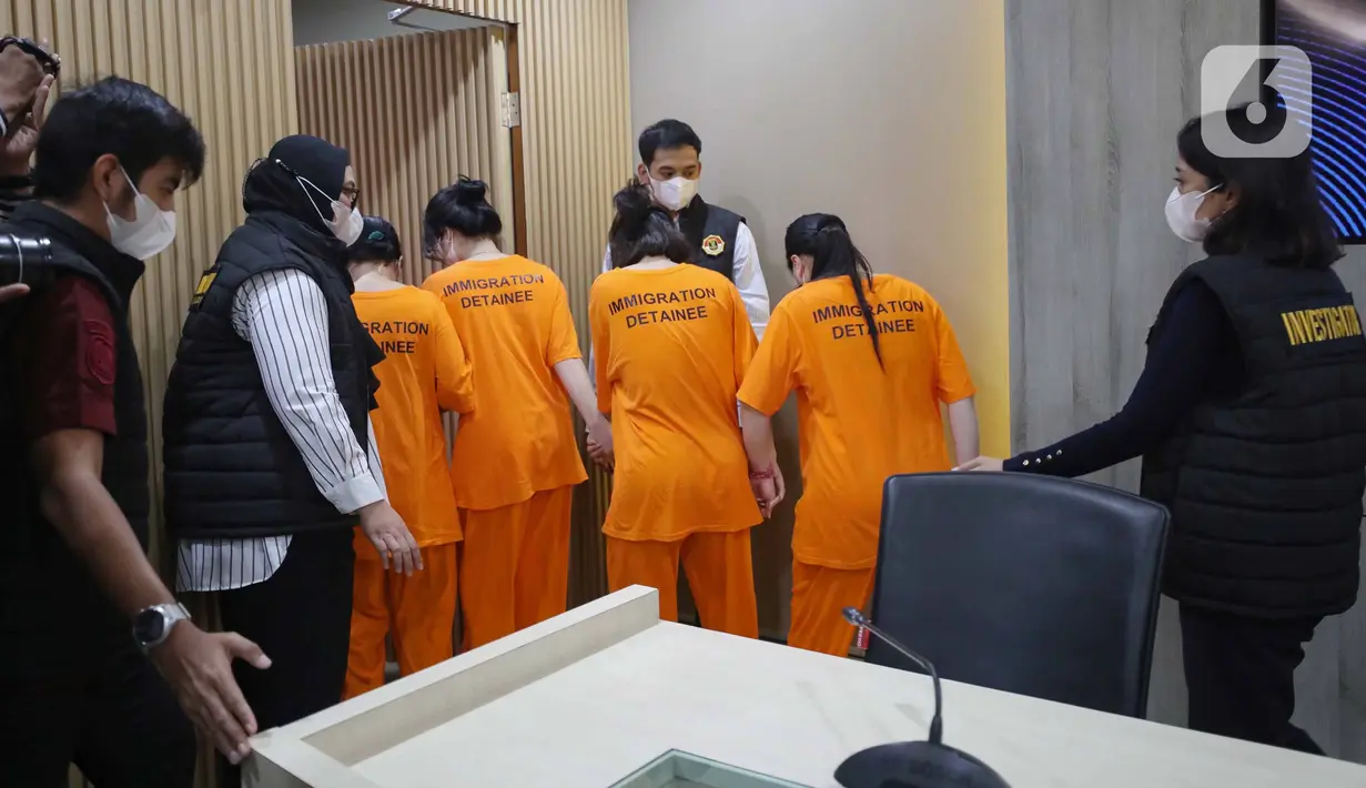 Petugas menggiring Warga Negara Asing (WNA) asal Vietnam yang tertangkap usai rilis penangkapan pelanggar izin tinggal di kantor Direktorat Jenderal (Ditjen) Imigrasi, Jakarta, Jumat (10/1/2025). (Liputan6.com/Angga Yuniar)