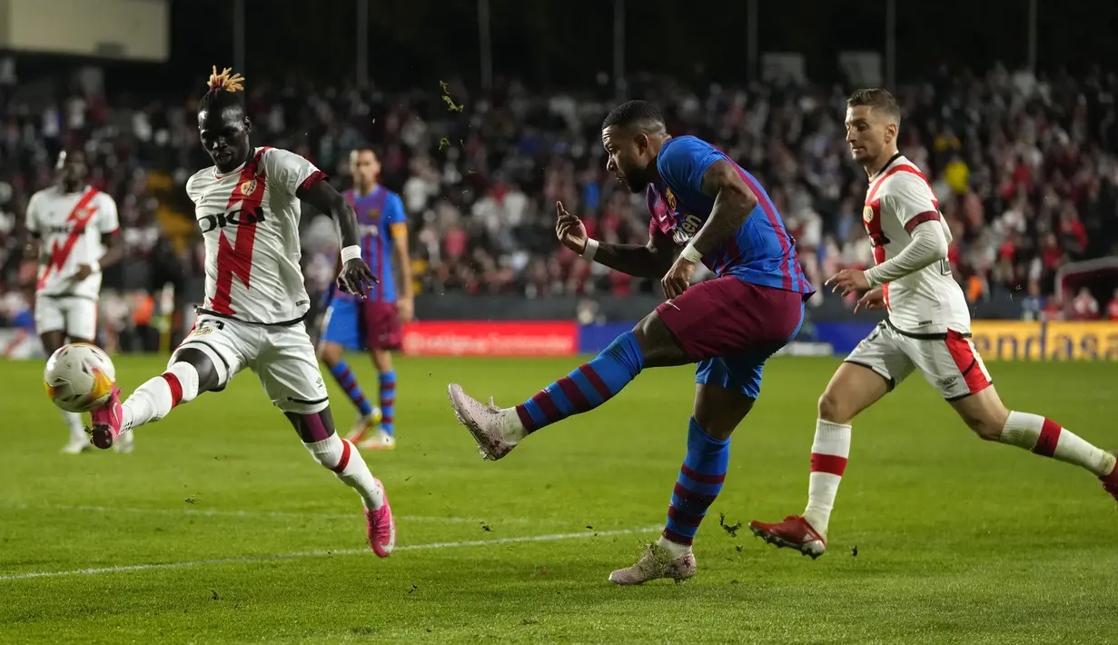 Pemain Barcelona Memphis Depay (tengah) melakukan tembakan ke gawang di depan pemain Rayo Vallecano Pathe Ciss (kiri) pada pertandingan La Liga Spanyol di Stadion Vallecas, Madrid, Spanyol, 27 Oktober 2021. Barcelona kalah 0-1. (AP Photo/Manu Fernandez)