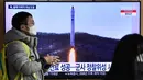 Seorang pria berjalan melewati layar televisi yang menayangkan siaran berita dengan rekaman file uji coba rudal Korea Utara, di sebuah stasiun kereta api di Seoul, Sabtu (31/12/20220). Otoritas Pyongyang belum memberikan pernyataan resmi terkait peluncuran terbaru tersebut. (Jung Yeon-je / AFP)
