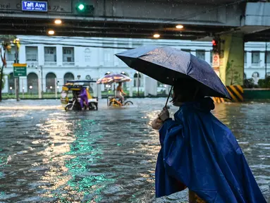 Orang-orang berjalan di sepanjang jalan yang tergenang banjir di Manila, Filipina pada 24 Juli 2024 di tengah hujan deras yang dibawa oleh Topan Gaemi. (Jam Sta Rosa/AFP)