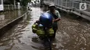 Seorang pria mendorong sepedanya melintasi banjir di kawasan Green Garden, Jakarta Barat, Selasa (25/2/2020). Hujan yang mengguyur kawasan Jakarta membuat kawasan tersebut tergenang banjir setinggi 60-80 cm. (Liputan6.com/Johan Tallo)