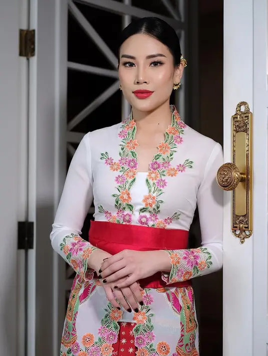 Angela Tanoesoedibjo tampil begitu menawan mengenakan kebaya model encim warna putih dengan aksen bordiran bunga warna-warni dan dipadukan dengan obi belt merah [Instagram/loritayoung_mua]
