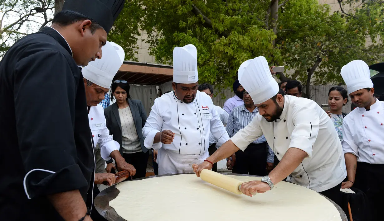Koki India meratakan adonan saat membuat roti goreng Bhatura, India, New Delhi, Kamis (6/4). Penyelenggara berharap Bhatura buatan mereka bisa memecahkan rekor Bhatura  terbesar di India. (AFP PHOTO / SAJJAD HUSSAIN)