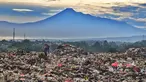 Warga yang berprofesi sebagai pemulung mengumpulkan sampah plastik dengan latar belakang Gunung Gede-Pangrango di Tempat Pembuangan Akhir Galuga, Bogor, Kamis (6/11/2025). Kementerian Lingkungan Hidup dan Kehutanan (KLHK) mendorong Tempat Pembuangan Akhir (TPA) sampah, khususnya yang berada di wilayah Jabodetabek dan masih menggunakan sistem open dumping, untuk segera melakukan penutupan tumpukan sampah (capping), atau beralih ke sistem yang lebih ramah lingkungan seperti lahan urug terkendali (controlled landfill) atau lahan urug saniter (sanitary landfill). (merdeka.com/Arie Basuki)