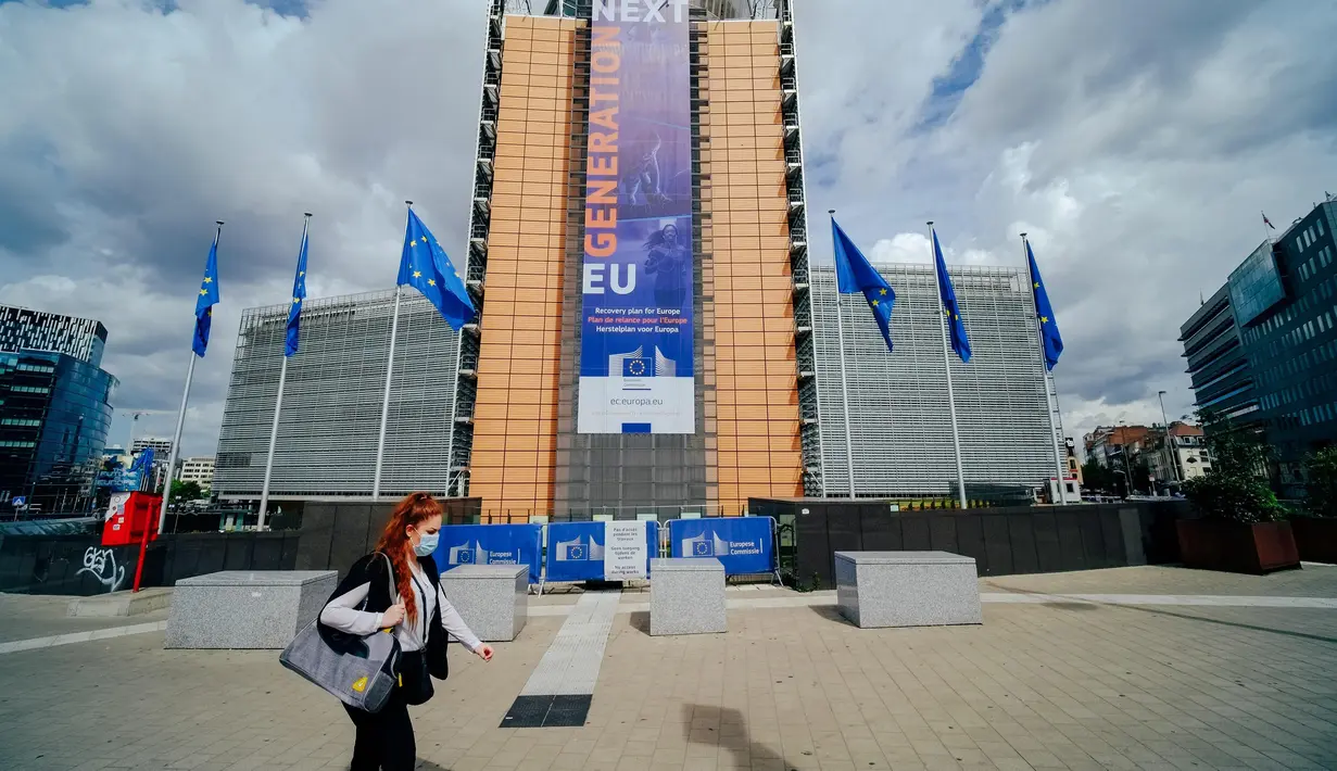 Seorang wanita yang mengenakan masker berjalan melewati markas Komisi Eropa di Brussel, Belgia, Selasa (7/7/2020). Komisi Eropa memprediksi Ekonomi Eropa akan menghadapi resesi lebih dalam akibat langkah-langkah pengendalian COVID-19 yang berkepanjangan. (Xinhua/Zhang Cheng)