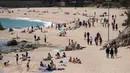 Orang-orang menikmati hari yang cerah di pantai Sa Conca di Castell-Platja D'Aro dekat Girona, Spanyol pada Rabu (31/3/2021). Masker telah wajib digunakan di Spanyol sejak Mei 2020 namun hanya di tempat yang tidak memungkinkan menjaga jarak minimal 2 meter. (Josep LAGO / AFP)