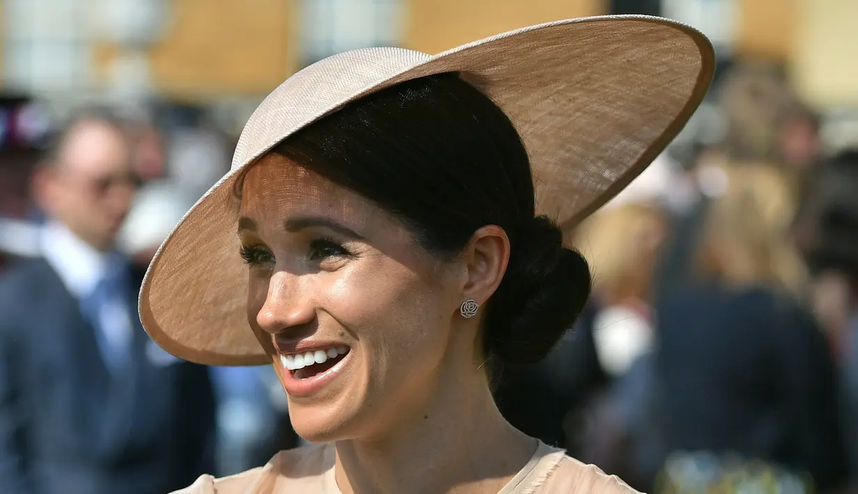 Duchess of Sussex, Meghan Markle menghadiri pesta kebun Istana Buckingham di London, Selasa (22/5). Royal hat senada dari Philip Treacy juga tak kalah menjadikan Meghan Markle tampil mengagumkan. (Dominic Lipinski/Pool Photo via AP)