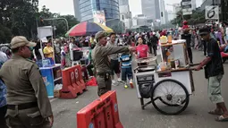 Satpol PP DKI Jakarta menertibkan PKL yang berdagang di kawasan Car Free Day, Bundaran HI, Jakarta, Minggu (20/1). Penertiban dilakukan karena telah membuat ketidaknyamanan bagi para pengunjung CFD yang ingin berolahraga. (Liputan6.com/Faizal Fanani)