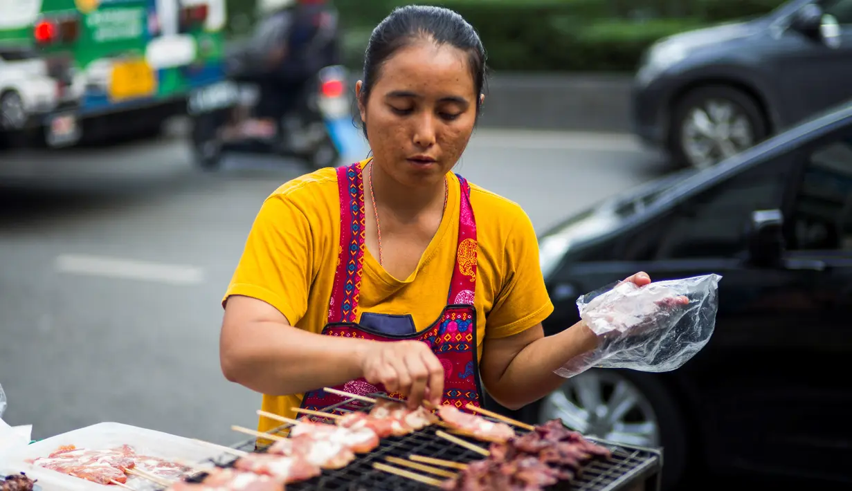 Seorang wanita memasak sate di gerobaknya di samping jalan di Bangkok, Thailand (20/9). Kota Bangkok, terkenal sebagai salah satu street food capital alias kota yang identik dengan makanan pinggir jalan. (AFP Photo/Jewel Samad)