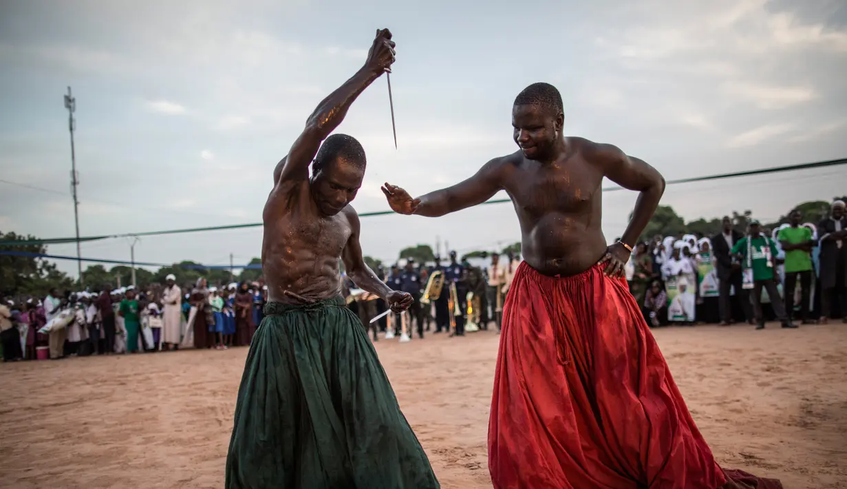 Warga kelompok etnis Joles mempersiapkan diri untuk menunjukkan kekuatan sihir yang berasal dari air spiritual, yang membuat mereka kebal dari senjata tajam saat kampanye Presiden Yahya Jammeh di Bikama, Gambia (24/11). (AFP/Marco Longari)