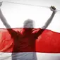 Demonstran digambarkan siluet oleh bendera nasional Belarusia tua saat unjuk rasa di Minsk, Belarus, Minggu (4/10/2020). Ratusan ribu warga Belarusia telah melakukan protes setiap hari sejak 9 Agustus pemilihan presiden. (AP Photo)