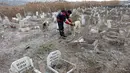 Seorang pekerja membelai seekor anjing di dekat kuburan di Pemakaman untuk tempat hewan peliharaan dimakamkan di Ankara, Turki pada 15 Januari 2022. Pemakaman hewan, yang didirikan oleh Kota Metropolitan Ankara pada tahun 1997, tidak digunakan lagi sejak tahun 2014. (Adem ALTAN/AFP)
