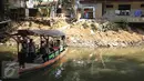 Sejumlah warga menggunakan kapal untuk akses menyebrang antar pemukiman di kawasan Kampung Pulo, Jakarta Timur, Kamis (23/7). Pemerintah Provinsi DKI Jakarta akan menertibkan bangunan liar yang ada di wilayah Kampung Pulo. (Liputan6.com/Faizal Fanani)