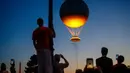 Orang-orang menyaksikan kaldron Olimpiade Paris 2024 saat matahari terbenam di Jardin des Tuileries di Paris pada 28 Juli 2024. (Dimitar DILKOFF/AFP)