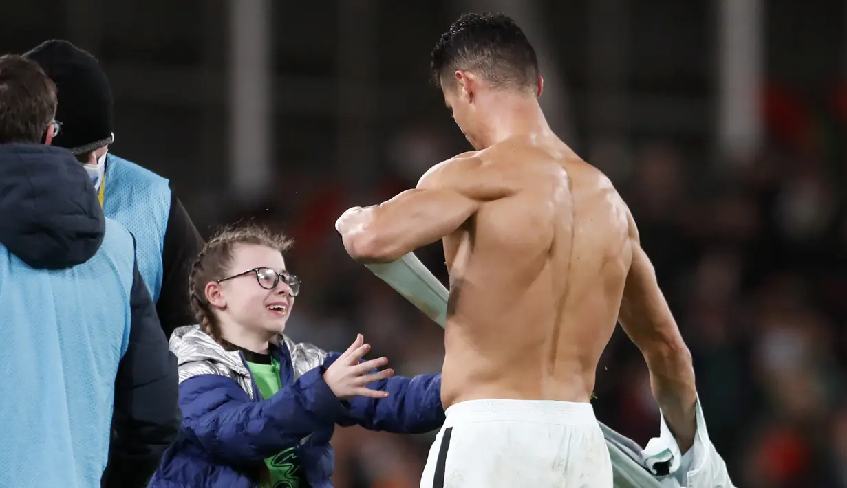 Penyerang Portugal Cristiano Ronaldo memberikan jerseynya untuk seorang fans cilik Irlandia yang berjalan ke lapangan pada akhir laga Grup A Kualifikasi Piala Dunia 2022 Zona Eropa di Stadion Aviva, Jumat (12/11/2021) dinihari WIB. Portugal ditahan imbang Irlandia 0-0. (AP /Peter Morrison)