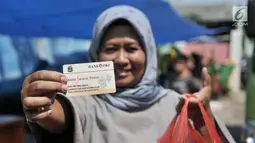 Warga menunjukkan KJP dan kebutuhan pokok yang dibeli dari Program Pangan Murah di RPTRA Utakara Beriman, Jakarta, Kamis (20/6/2019). Program tersebut juga bertujuan meningkatkan gizi warga pemegang Kartu Lansia Jakarta, PPSU, PHL, PJLP, UMP, serta penghuni Rusun Pemda. (merdeka.com/Iqbal S Nugroho)