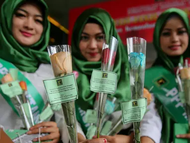 Simpatisan perempuan muda PPP kubu Djan Faridz membagikan bunga kepada pegawai dan pengunjung di Kantor Kementerian Hukum dan Ham, Jakarta, Senin (11/1). Aksi damai tersebut mendesak penyelesaian konflik pengurusan partai PPP. (Liputan6.com/Faizal Fanani)