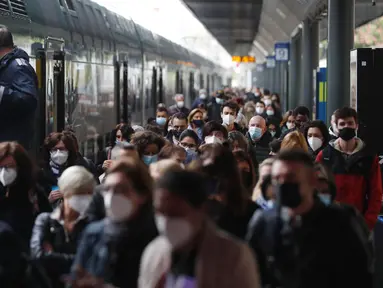 Para penumpang yang mengenakan masker berjalan di peron setelah turun dari kereta regional di stasiun Cadorna di Milan, Senin (26/4/2021). Italia kembali dibuka secara bertahap pada hari Senin setelah enam bulan memberlakukan lockdown untuk menghambat penyebaran Covid-19. (AP Photo/Antonio Calanni)